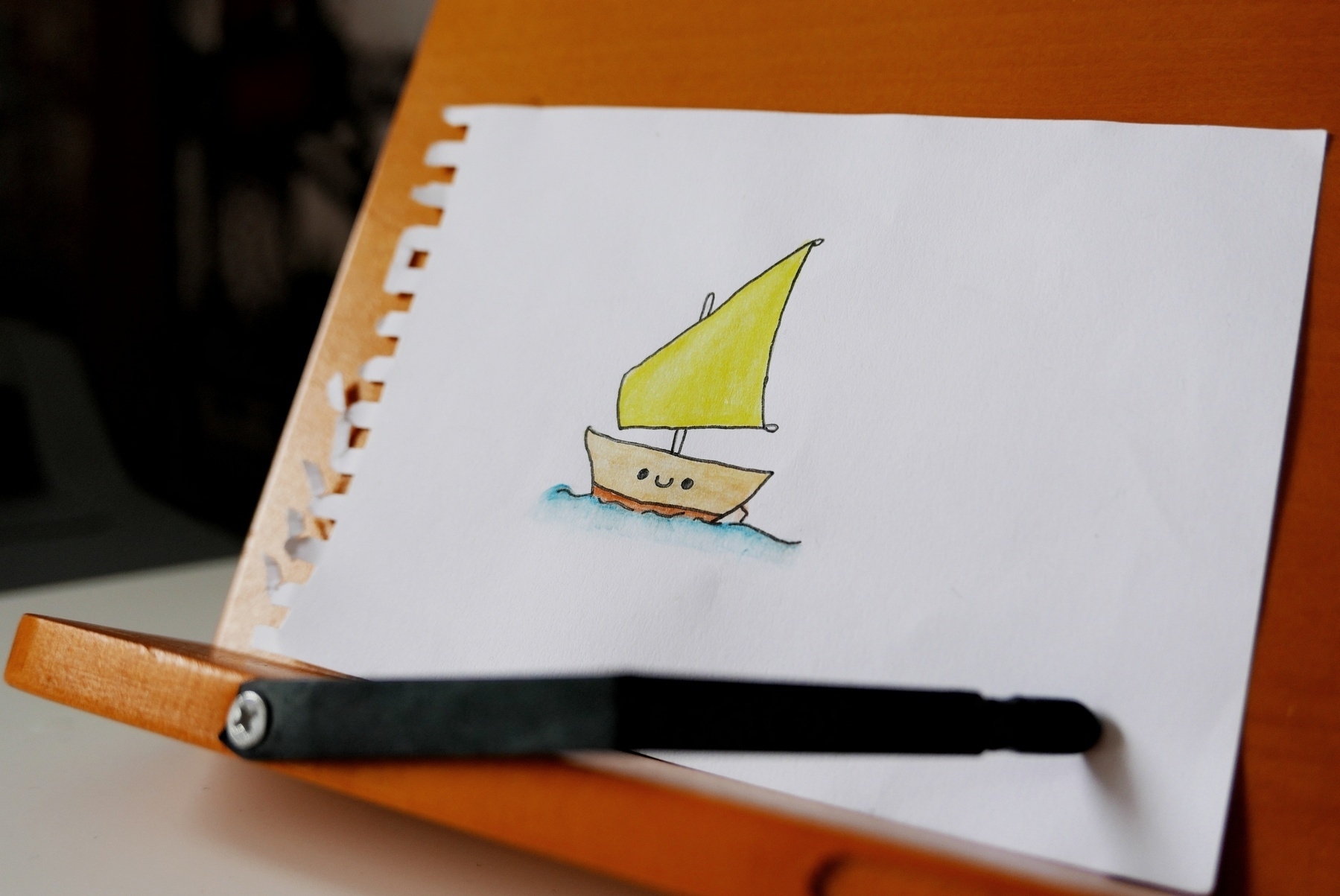 A doodle of a little boat in a kawaii style on a wooden book stand