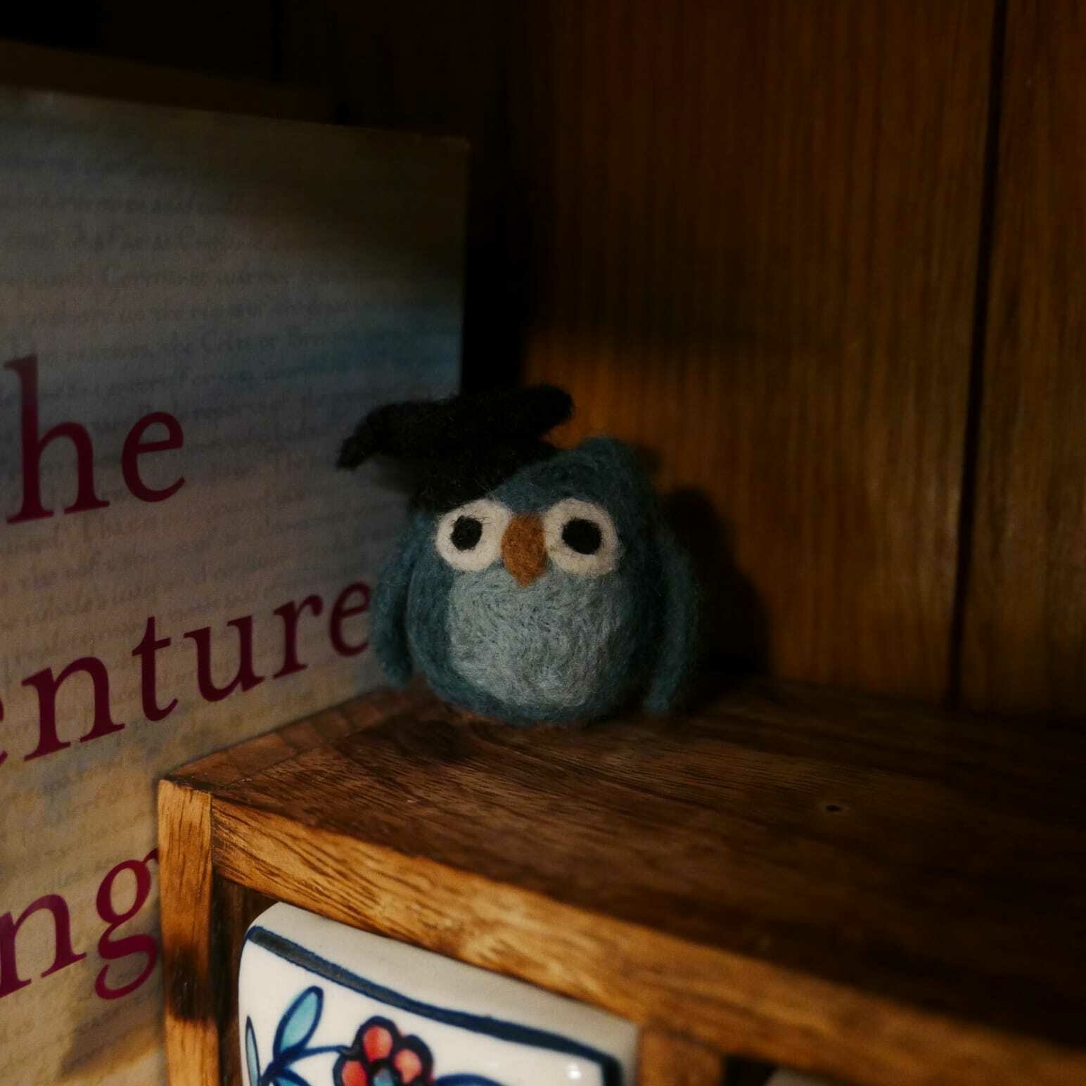 A photo of a small felt owl wearing a graduation cap